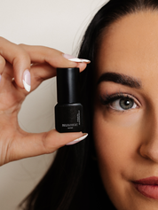 Woman holding a small bottle of Bellamarque eyelash extension glue near her face