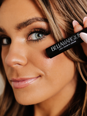 Woman holding BellaMarque Lash Growth Serum near her eye.