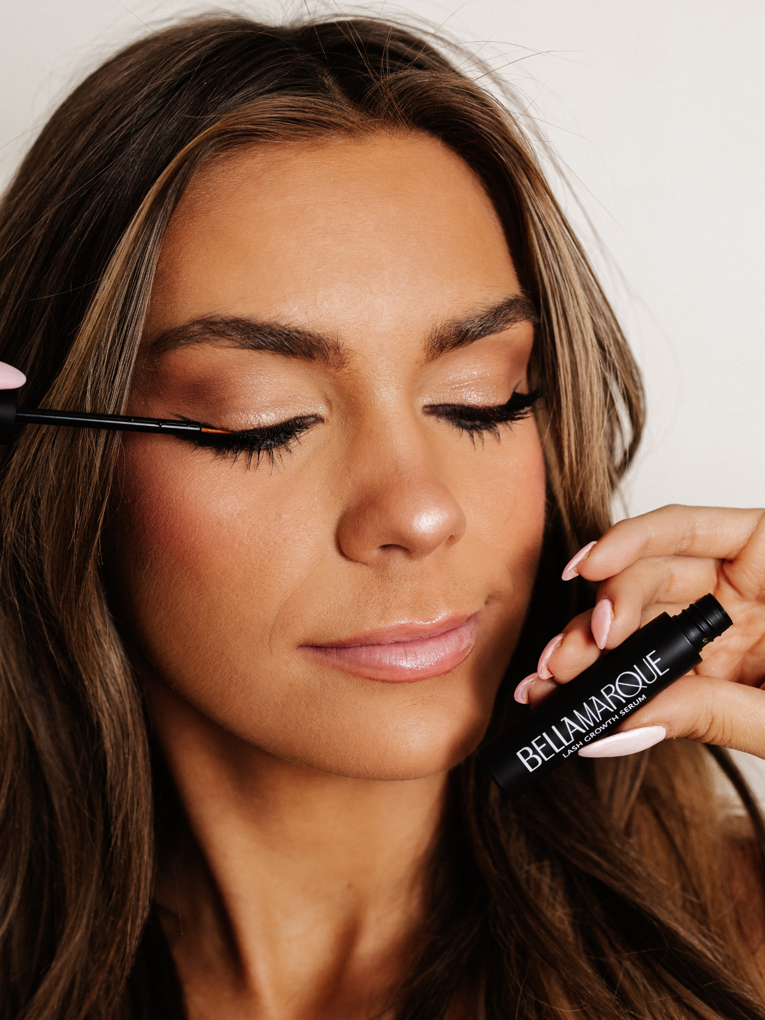 Woman applying BellaMarque Lash Growth Serum to upper eyelashes.