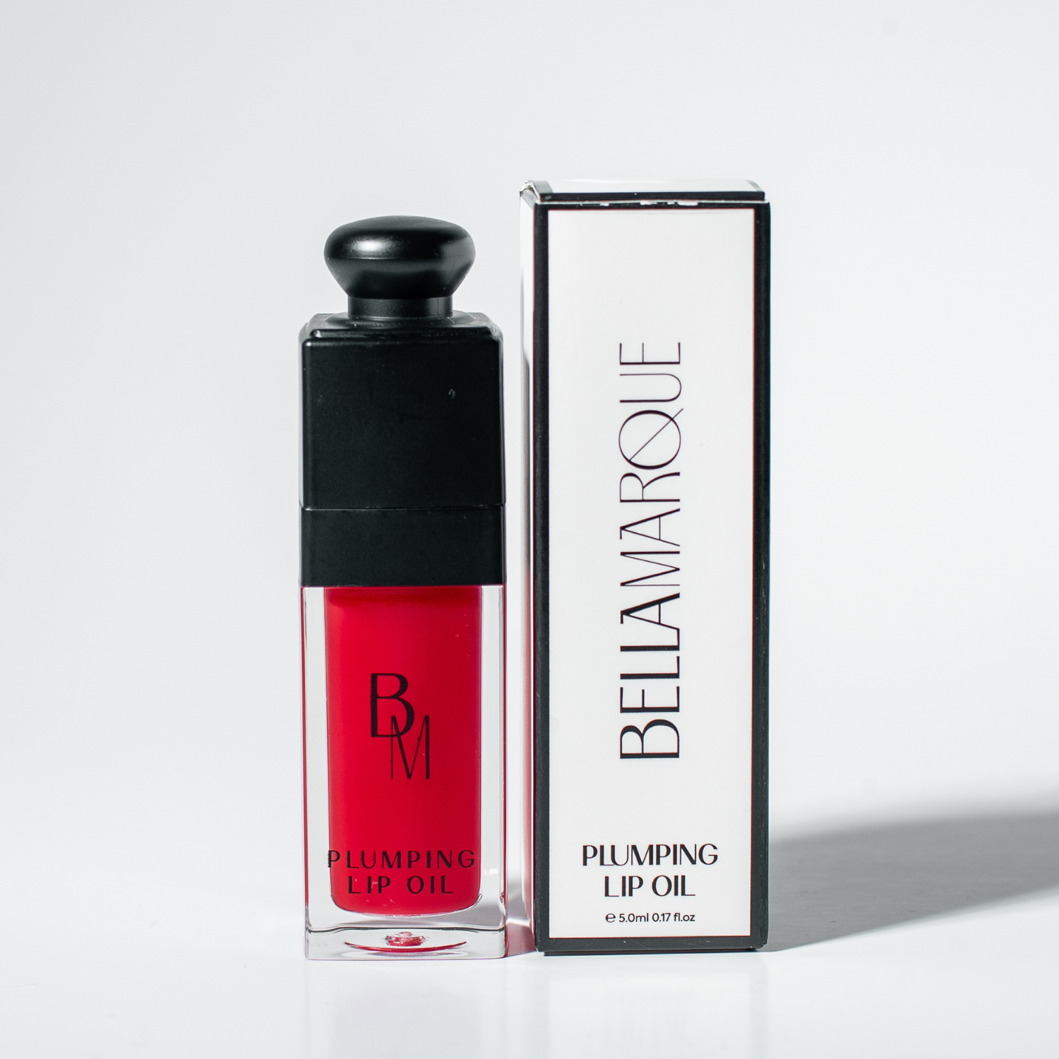 Red lip oil beside its packaging on white surface