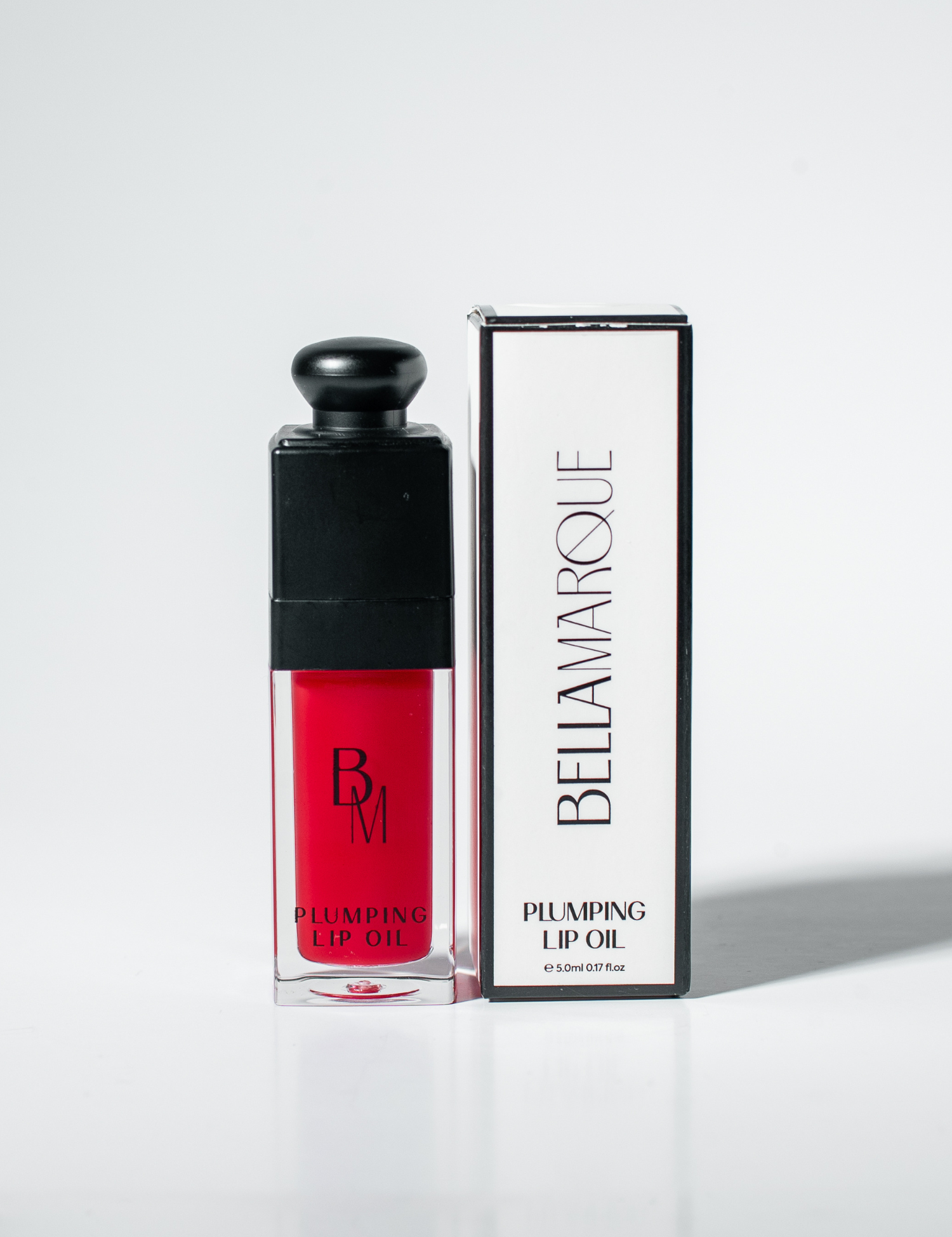 Red lip oil beside its packaging on white surface