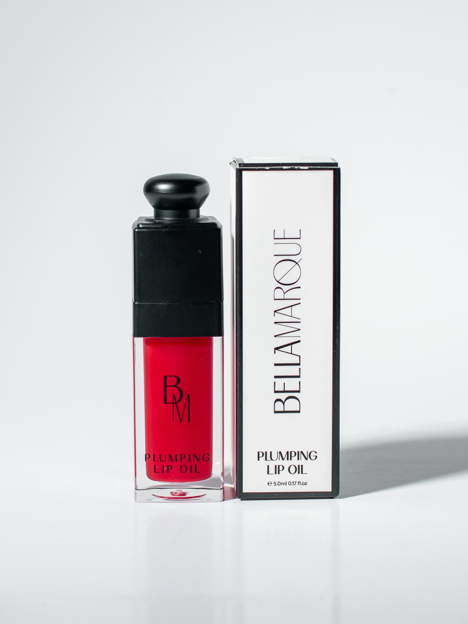 Red lip oil beside its packaging on white surface