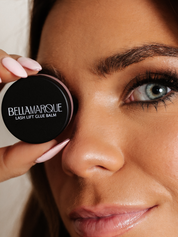 Woman holding black lash balm container near eye